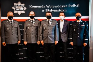 Policjanci stoją przy ściance z napisami.