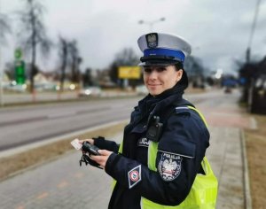 Policjantka stoi na chodniku i uśmiecha się.