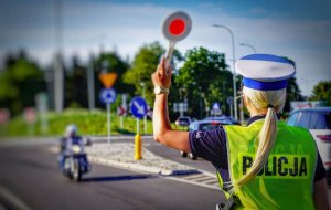 Policjantka zatrzymuje tarczą pojazd.