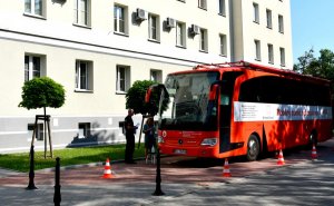 Budynek KWP przed którym zaparkowany jest czerwony autobus