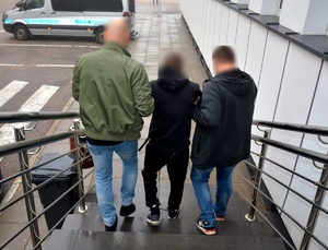 Policjanci prowadzą zatrzymanego i wykonują z nim czynności