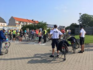 Policjanci z patrolu rowerowego stoją na na parkingu w obecności uczestników rajdu rowerowego.