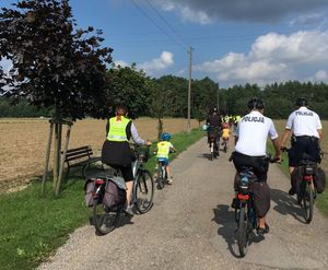 Policjanci na rowerach jada obok uczestników rajdu rowerowego