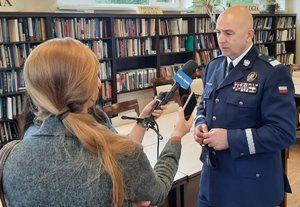 komendant wojewódzki siedzi obok innych osób przy stole prezydialnym podczas konferencji prasowej, na stole poustawiane mikrofony