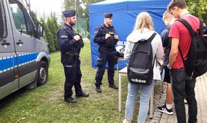przy namiocie z napisem policja i obok benerem &quot;dołącz do nas&quot; kilkanaścioro licealistów ogląda materiały promocyjne