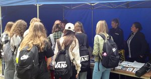 przy namiocie z napisem policja i obok benerem &quot;dołącz do nas&quot; kilkanaścioro licealistów ogląda materiały promocyjne