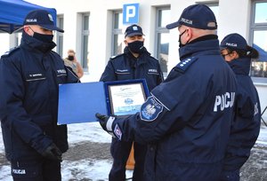 3 policjanci stoją obok siebie jeden trzyma pamiątkową tablicę