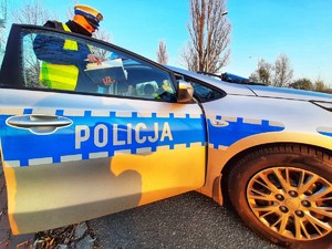 policjant stoi przy radiowozie