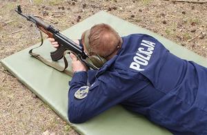 policjant leży z bronią trzymaną w obu rękach