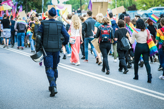 policjant idzie obok uczestników marszu