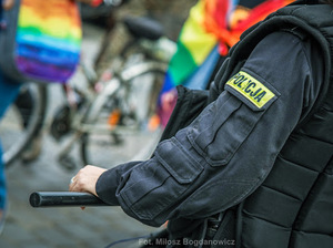 ramię policjanta w tle uczestnicy marszu