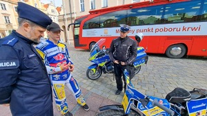 policjanci i żużlowiec oglądają motocykle