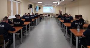 policjanci siedzą w ławkach w sali