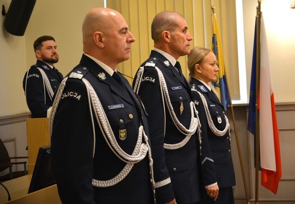 3 POLICJANTÓW STOI W SZEREGU - ZDJĘCIE Z BOKU TEGO  SZEREGU