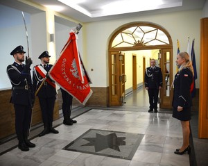 Zdjęcie przedstawia sztandar policyjny, obok którego stoi 5 policjantów.