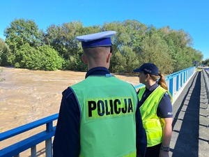 Zdjęcie przedstawia policjantów, stojących przy moście.