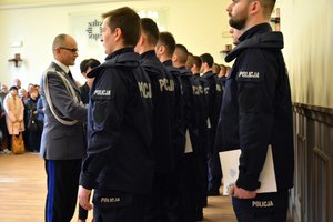 Nowo przyjęci policjanci otrzymują akty ślubowania z rąk komendanta