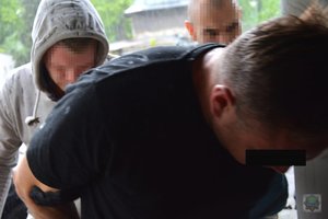 Policjanci służby kryminalnej prowadzą zatrzymanego