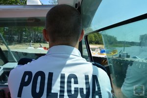 policjant za sterami łodzi dopływa do brzegu