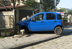 niebieski samochód po zderzeniu z murem posesji