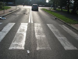 zniszczone znaki drogowe i strzępy karoserii samochodowej na drodze