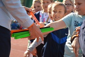 dzieci wyciągają ręce po odblaski, widać dłonie mężczyzny, który im te odblaski wręcza