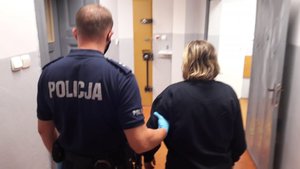 policjant prowadzi zatrzymaną kobietę