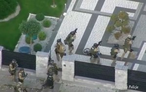 policjanci realizujący zatrzymanie - funkcjonariusze w moro przy bramie posesji i przy posesji