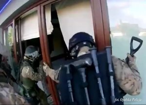 policjanci realizujący zatrzymanie - funkcjonariusze w moro przy bramie posesji i przy posesji