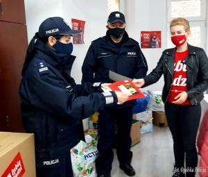 policjanci wręczają paczki przedstawicielom akcji szlachetna paczka. w tle choinka