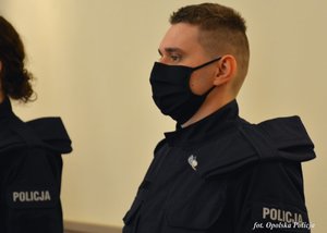 policjant stoi na tle ściany