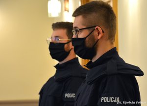 policjant stoi na tle ściany