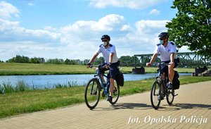 2 policjantów jedzie rowerami ścieżką w parku