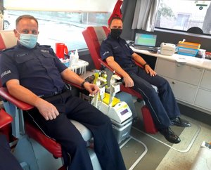 dwaj policjanci siedzą obok siebie na fotelach do pobierania krwi